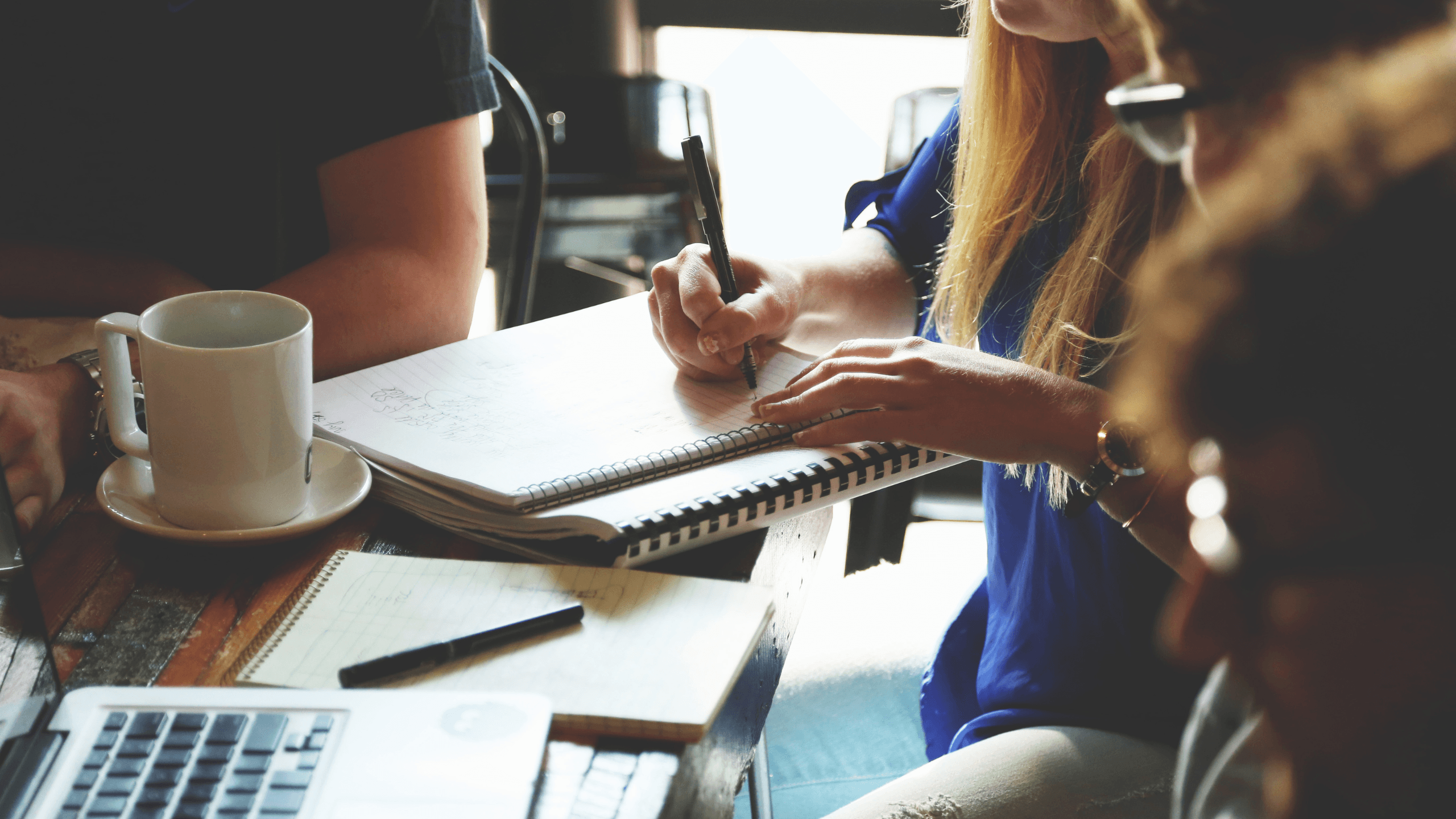 Writers collaborating with notebooks and coffee
